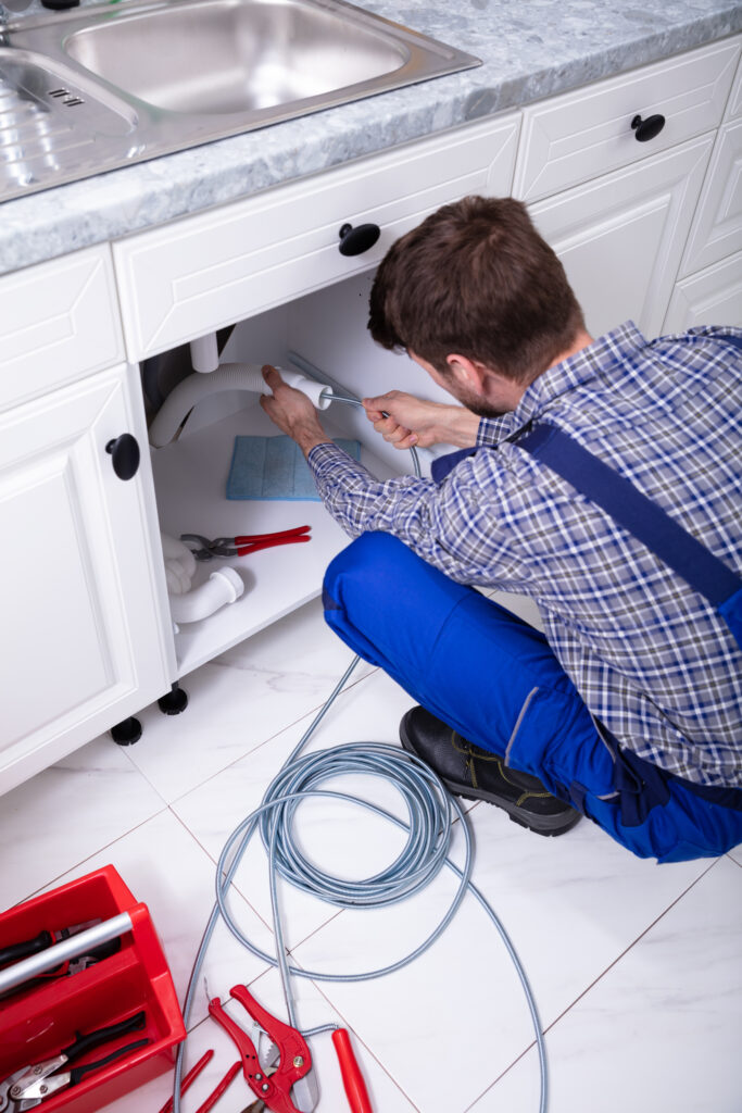 Plumber cleaning drain under sink