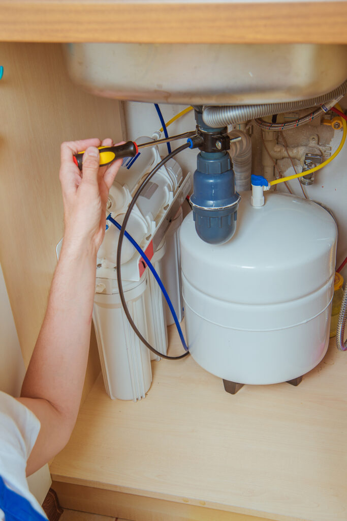 plumber fixing water filtration under sink