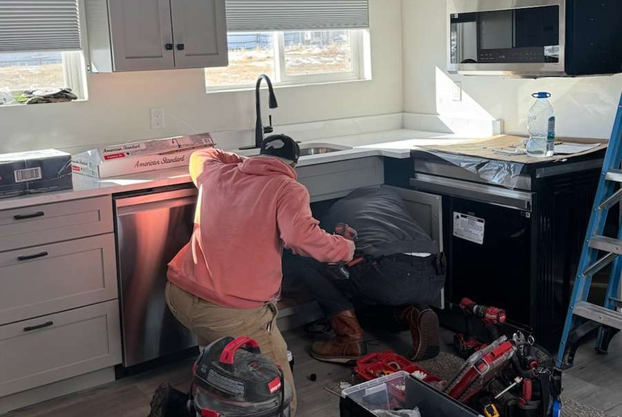 Plumber fixing pipes under sink