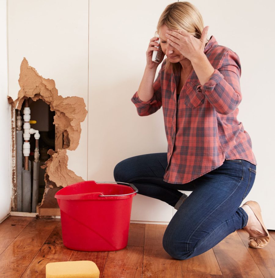 Middle,Aged,Woman,With,A,Burst,Water,Pipe,Phoning,For Woman with a busted pipe called plumber for help